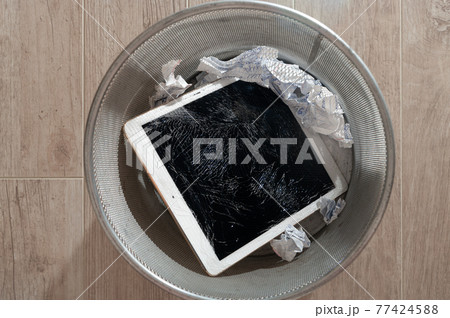Modern tablet with highly broken screen in the litter bin. Close-up. 77424588