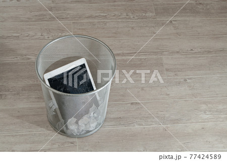 Modern tablet with highly broken screen in the litter bin. 77424589