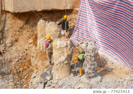 SEREMBAN, MALAYSIA -MARCH 05, 2021:  Construction workers cutting concrete bore pile up to the determined level at the construction site. Stage fo work before fabricating the pile cap.   77425413