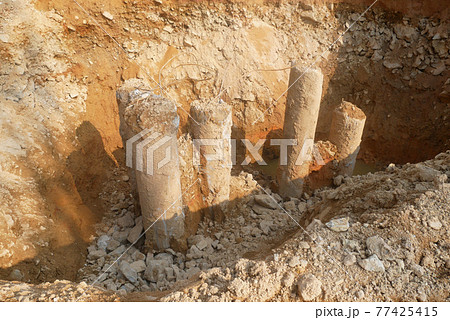 SEREMBAN, MALAYSIA -MARCH 05, 2021:  Construction workers cutting concrete bore pile up to the determined level at the construction site. Stage fo work before fabricating the pile cap.   77425415