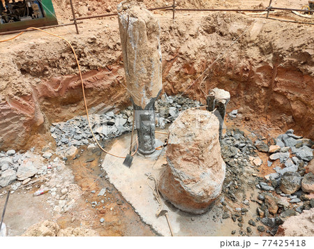 SEREMBAN, MALAYSIA -MARCH 05, 2021:  Construction workers cutting concrete bore pile up to the determined level at the construction site. Stage fo work before fabricating the pile cap.   77425418
