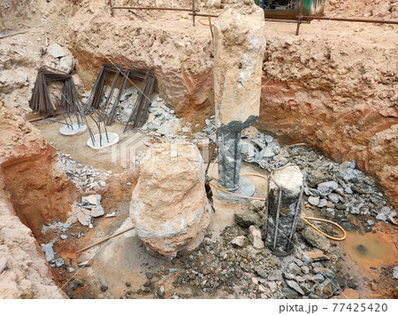 SEREMBAN, MALAYSIA -MARCH 05, 2021:  Construction workers cutting concrete bore pile up to the determined level at the construction site. Stage fo work before fabricating the pile cap.   77425420