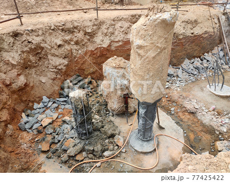 SEREMBAN, MALAYSIA -MARCH 05, 2021:  Construction workers cutting concrete bore pile up to the determined level at the construction site. Stage fo work before fabricating the pile cap.   77425422