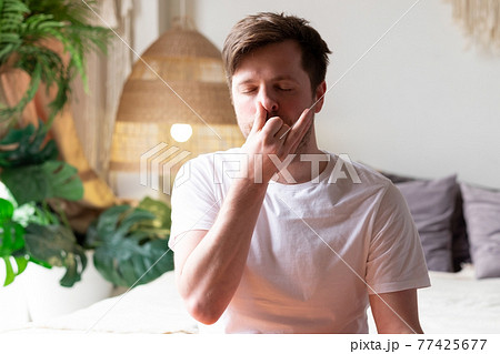 Caucasian mature man practicing yoga sitting, making Alternate Nostril Breathing 77425677