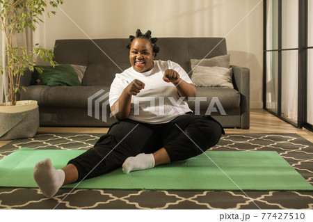 Multiracial woman improving her health while doing exercises on the mat at home 77427510