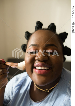 Woman blogger with perfect makeup touching with brush to her chic 77427678