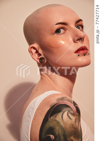 Bald unladylike woman with patches under her eyes posing with serious emotions 77427714