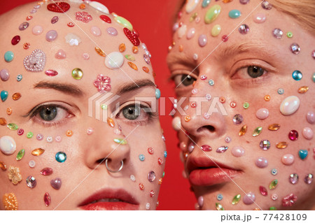 Albino boy with decor at his face looking at the camera while bonding to the mannish bald female 77428109