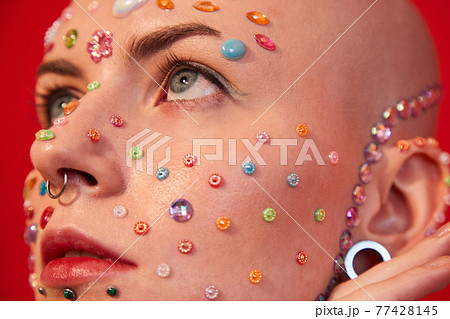Woman with naked shoulders and decor at her face posing and looking away 77428145