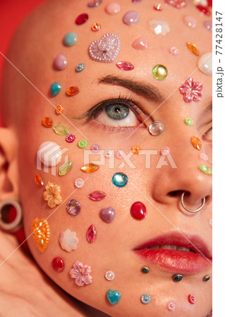 Unladylike woman with piercing and decor at her face looking at up with serious expression 77428147