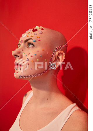 Mannish female with piercing and decor at her face looking away 77428153