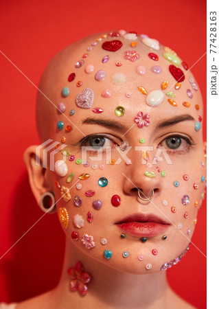 Woman with naked shoulders and decor at her face posing and looking at the camera 77428163