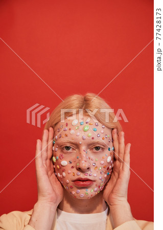Albino man with decor at his face frames his head with his hands Albino man with decor at his face frames his head with his hands 77428173