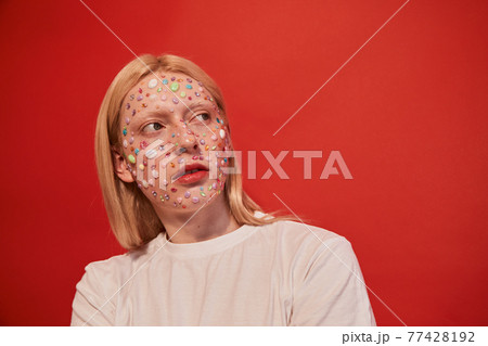 Feminine man with rhinestones at his face that accentuate his unusual appearance looking away Feminine man with rhinestones at his face that accentuate his unusual appearance looking away 77428192