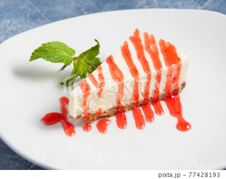 cheesecake with strawberry sauce, garnished with mint on a white plate cheesecake with strawberry sauce, garnished with mint on a white plate 77428193