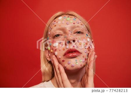 Long haired guy with rhinestones at his face holding his hands near his head Long haired guy with rhinestones at his face holding his hands near his head 77428213