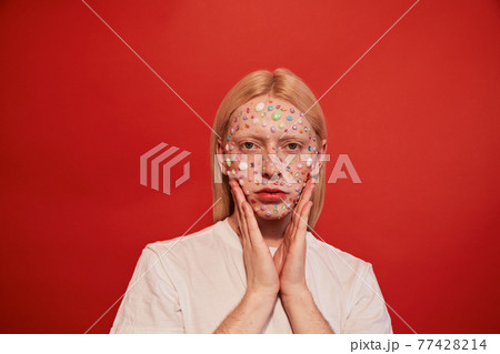 Feminine man with face covered with rhinestones standing at the studio and posing 77428214