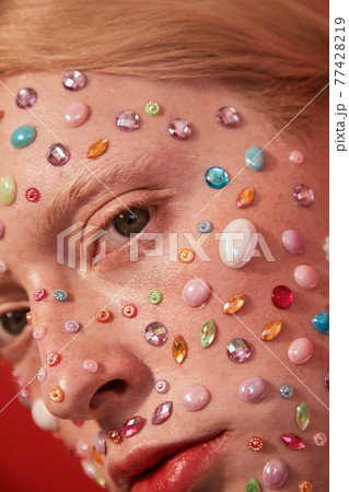 Albino womanly guy with decor of the rhinestones at his face looking at the camera Albino womanly guy with decor of the rhinestones at his face looking at the camera 77428219