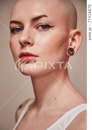 Young woman with tattoos and piercing posing on white background 77428876