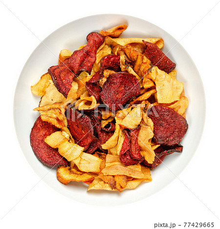 Mixed root vegetable crisps, in a white bowl. Mix of sliced root vegetables, parsnips, beetroots and carrots, fried in sunflower oil, with sea salt. Close-up from above, over white, macro food photo. Mixed root vegetable crisps, in a white bowl. Mix of sliced root vegetables, parsnips, beetroots and carrots, fried in sunflower oil, with sea salt. Close-up from above, over white, macro food photo. 77429665