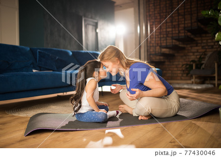 Woman meditating at living room with her daughter while bonding to each other 77430046
