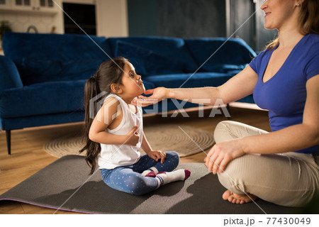 Woman meditating at home and practicing yoga while sitting at floor with her kid 77430049