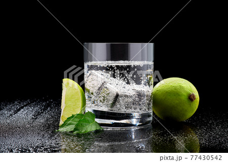 Glass of Soda or Coctail with steel cooling cubes on dark glass background Glass of Soda or Coctail with steel cooling cubes on dark glass background 77430542