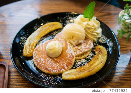 Pancake dessert snack menu served with banana split topped with butter, ice cream and honey syrup 77432922