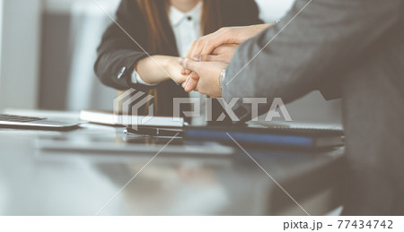 Unknown business people group joining hands in modern office. Businessmen and women making circle with their hands as a team, close-up Unknown business people group joining hands in modern office. Businessmen and women making circle with their hands as a team, close-up 77434742