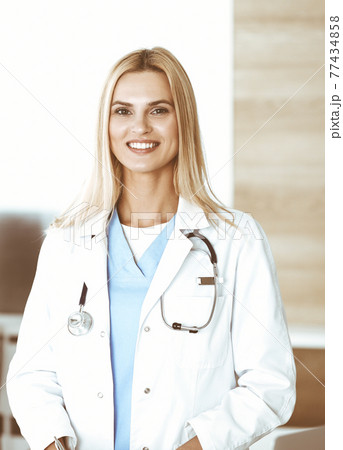 Woman-doctor at work in clinic happy of her profession. Blond female physician controls medication history record and medical exam results. Medicine concept Woman-doctor at work in clinic happy of her profession. Blond female physician controls medication history record and medical exam results. Medicine concept 77434858