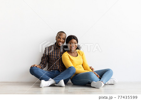 Portrait Of Happy Black Couple Sitting On Floor In Empty Flat 77435599