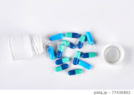 Blue medical capsules and white bottle. 77436802