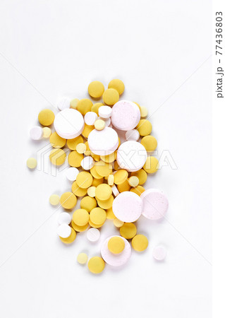 Pile of white and yellow pills. 77436803