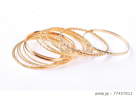 Gentle golden bracelets over white background. Gentle golden bracelets over white background. 77437012