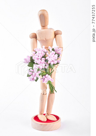 Wooden dummy holding pink flowers. Wooden dummy holding pink flowers. 77437255
