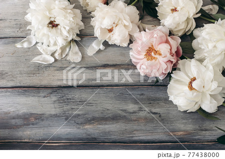 Decorative floral frame, banner made of pink and white peonies flowers. Old grey wooden table background. Empty copy space. Flat lay, top view. Picture for blog. Summer wedding or birthday concept. 77438000