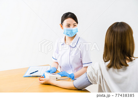 患者の血圧を測る看護師 患者の血圧を測る看護師 77438385