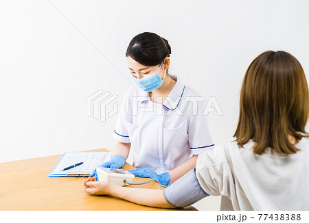 患者の血圧を測る看護師 77438388