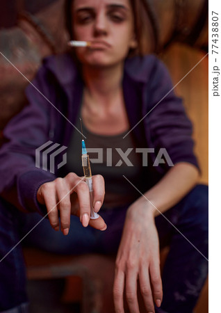 Drug addict female person holds syringe Drug addict female person holds syringe 77438807