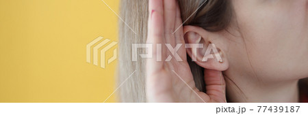 Young hard of hearing woman holding her hand near ear 77439187
