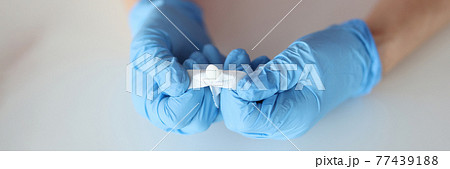 Doctors hands in rubber gloves opening rectal suppository closeup 77439188