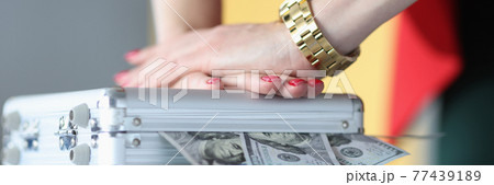 Female hands closing metal suitcase with dollar bills closeup 77439189