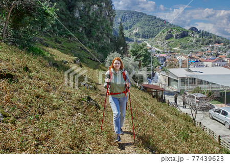 Trekking poles are used by young woman when going uphill. 77439623
