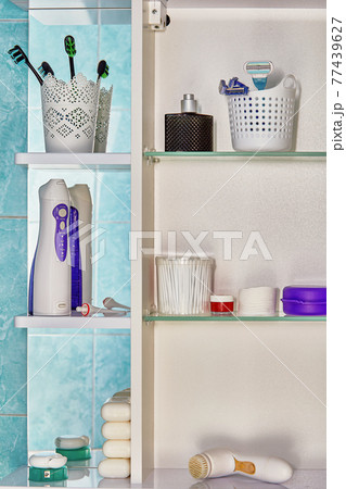 Personal hygiene items, including an oral irrigator, are located on shelves of wall cabinet in bathroom. 77439627