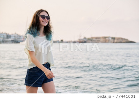 Beautiful teenager girl in sunglasses with dyed blue hair on sea beach, copy space Beautiful teenager girl in sunglasses with dyed blue hair on sea beach, copy space 77441001