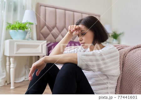 Sad, frustrated, depressed mature woman sitting at home on the floor 77441601