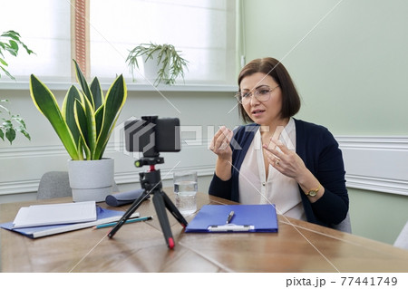 Mature confident woman counselor recording video stream, online consultation Mature confident woman counselor recording video stream, online consultation 77441749