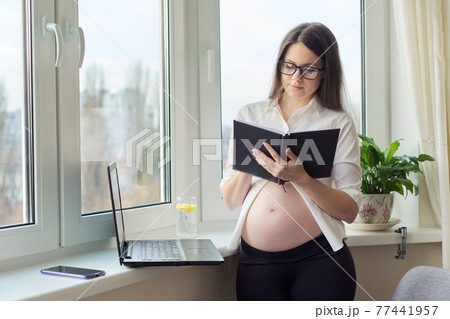 Pregnant business woman working at home with laptop, female writing in notebook 77441957