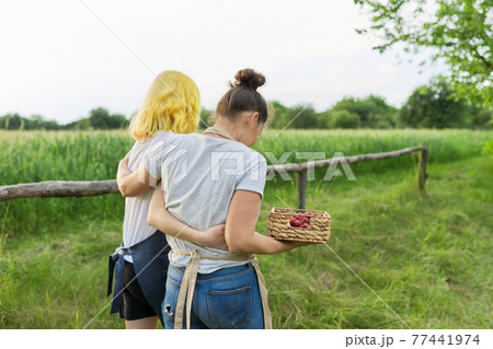 Back view on walking mother and teenage daughter hugging in together on farm Back view on walking mother and teenage daughter hugging in together on farm 77441974