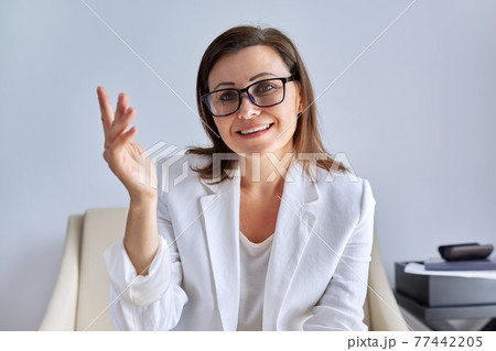 Positive talking middle aged business woman looking at webcam Positive talking middle aged business woman looking at webcam 77442205